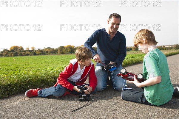 Father tinkering on a remote-controlled model car with his sons