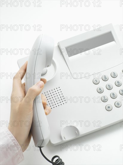 Woman picking up the handset of a telphone