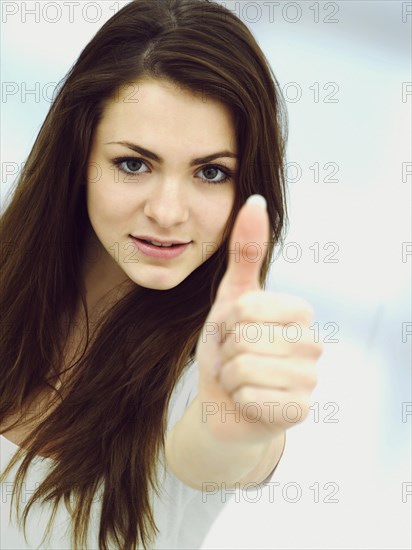 Young woman making a thumbs up gesture