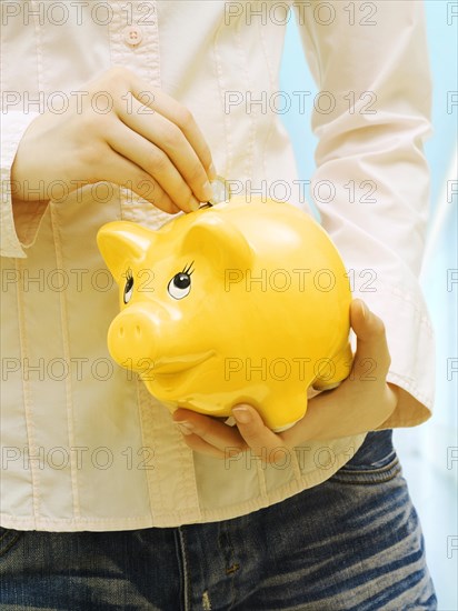 Girl putting euro coin into in piggy bank