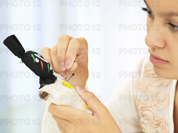 Woman sticking needles into a voodoo doll