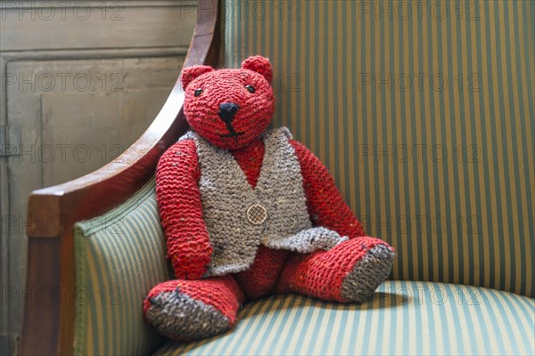 Knitted red teddy bear with vest on striped armchair - Photo12 ...