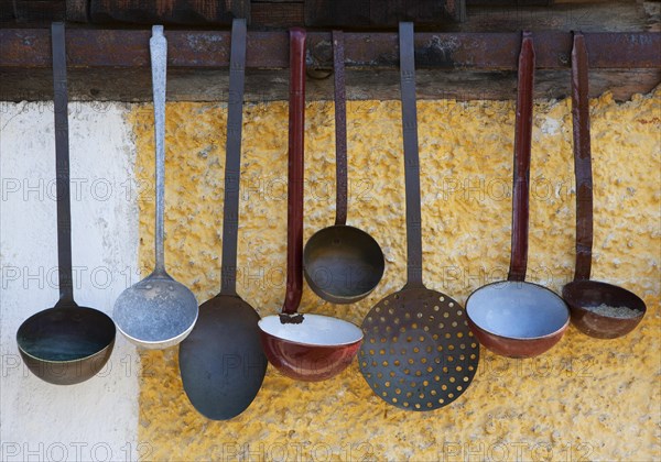 Various ladles hanging on a wall of a farm