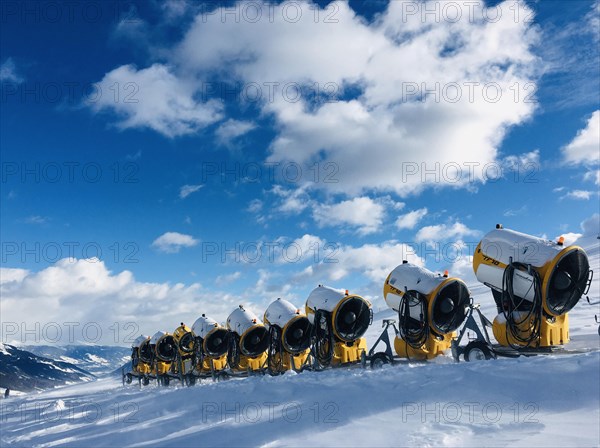 Many snow cannons stand one behind the other next to the skiing trail