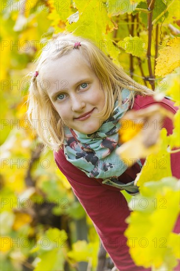Girl looking through a row of vines