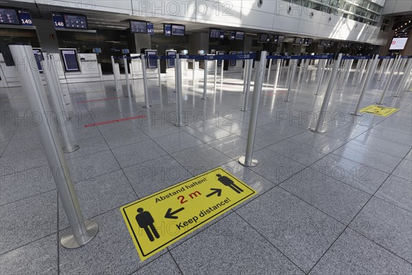 Sign with distance rule in front of the deserted baggage check, flight ban due to corona pandemic