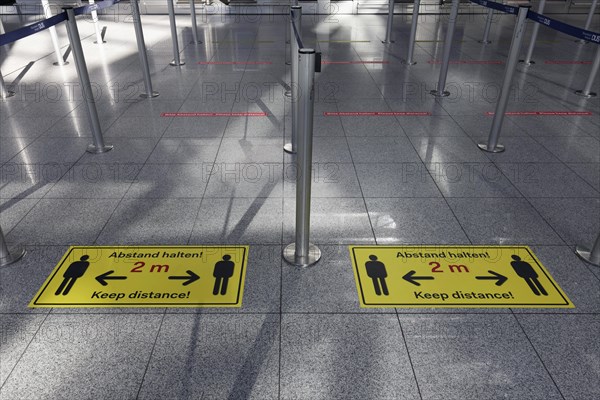 Signs with distance rule in front of the deserted baggage check, flight ban due to corona pandemic
