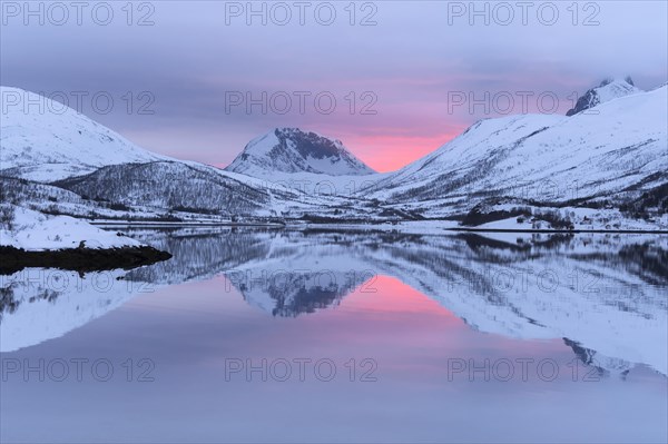 Snow-covered peaks in the evening light reflected in the lake