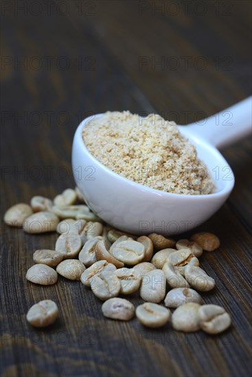 Green coffee beans and unroasted coffee powder in spoon