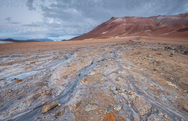 Water from a hot spring flows over the red plain
