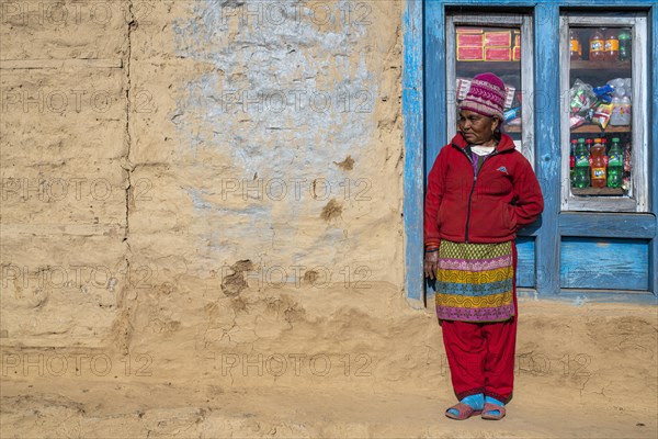 A local woman is standing in front of the window of her shop