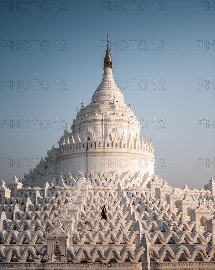 Buddhist monk stands with red umbrella in front of Hsinbyume Pagoda