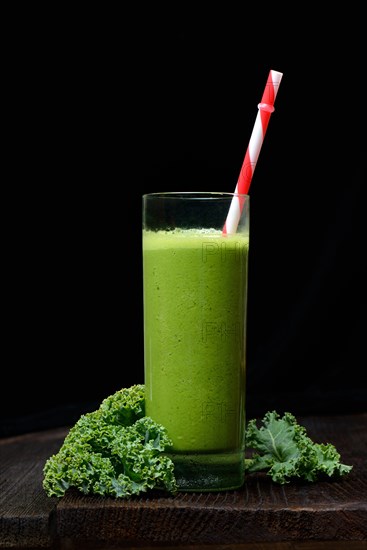 Kale smoothie in glass with drinking straw