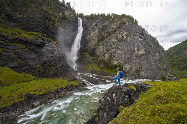 Hiker standing on rocks by river Driva