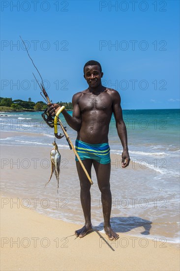 Man with fresh fished squid on the beach Praia dos Governadores