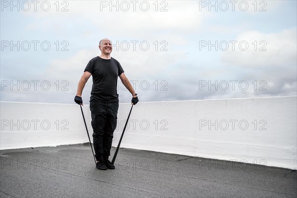 A man exercising with rubber band on the rooftop during lockdown