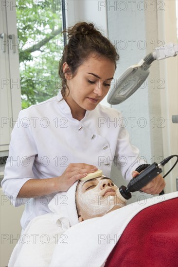 Application of the white face pack with moisture and vitamins in connection with the brush grinder for peeling the skin in practical lessons. Training as a beautician at the vocational school