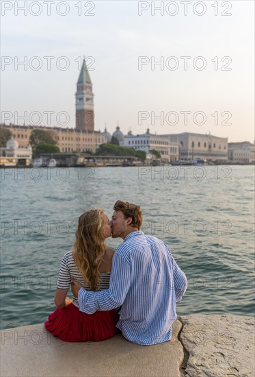 Young couple in love sitting at the sea and kissing