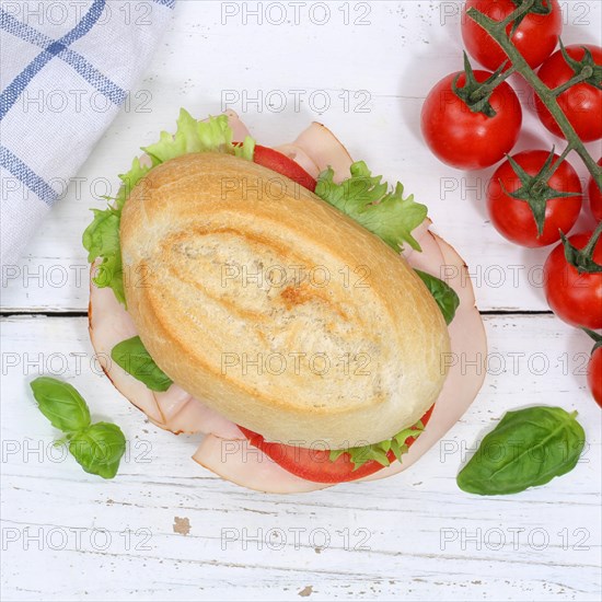 Roll sandwich baguette topped with ham from above on wooden board