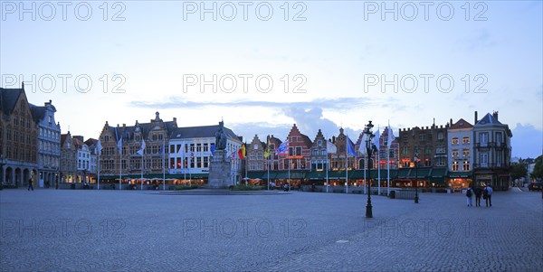 Market with statue of Jan Breydel and Pieter De Coninck and residential buildings on the north side of the square at dusk