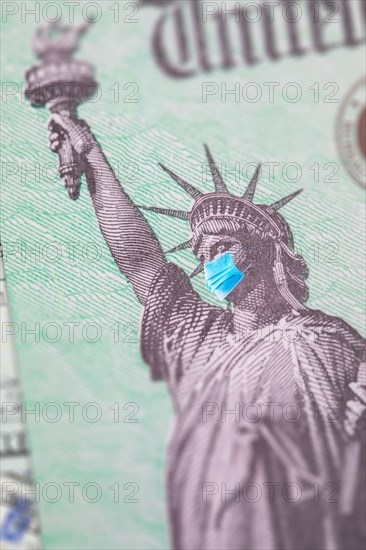 United states IRS stimulus check with statue of liberty wearing medical face mask