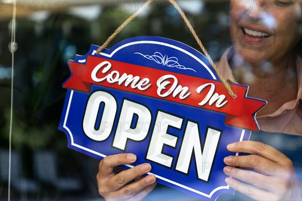 Happy Female Store Owner Turning Open Sign in Window