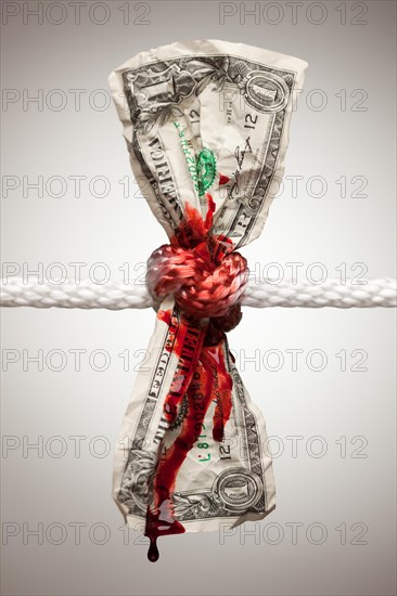 Wrinkled american dollar tied up and bleeding in rope