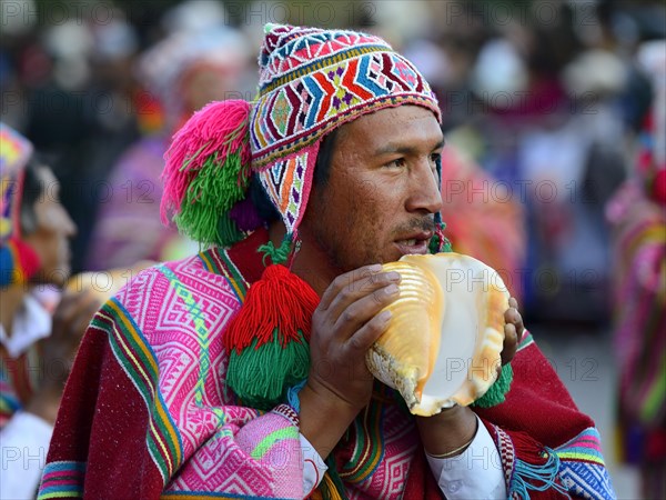 Indigenous man blows conch shell during parade on eve of Inti Raymi