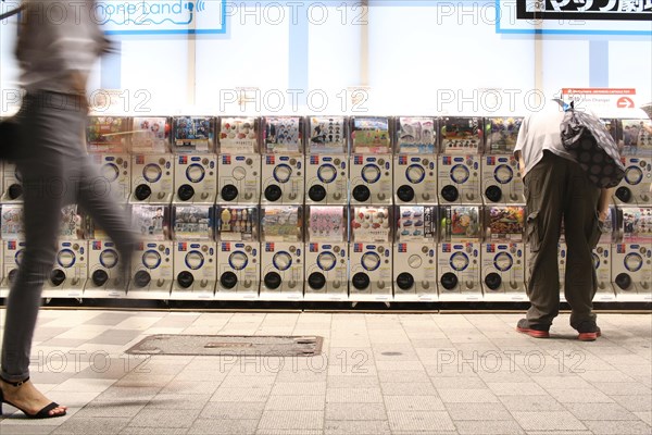 Man using Gashapon capsule toy vending machines in Akihabara