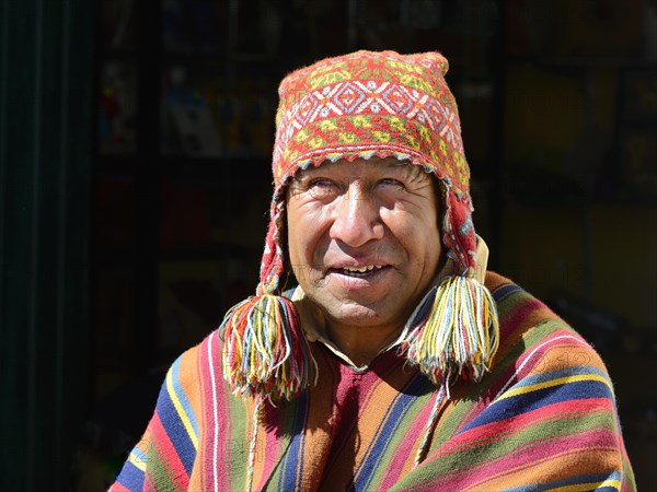 Indigenous man in colorful poncho and cap