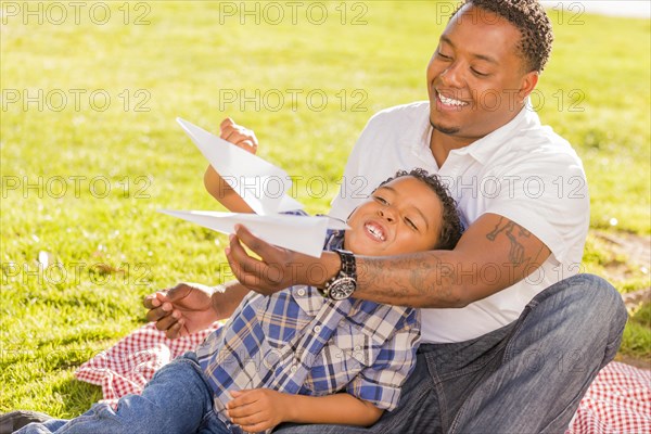 Happy african american father and mixed-race son playing with paper ...