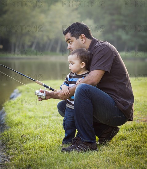 Happy young ethnic father and son fishing at the lake