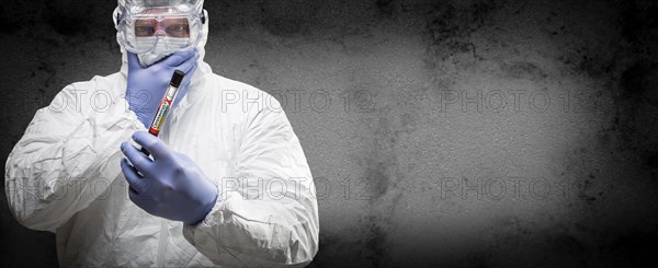 Male doctor or nurse in hazmat gear holding positive coronavirus test tube banner