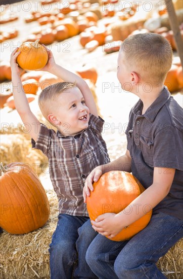 Two boys at the pumpkin patch talking about their pumpkins and having fun on a fall day