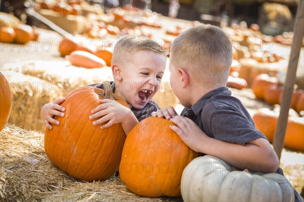 Two boys at the pumpkin patch talking about their pumpkins and having fun on a fall day