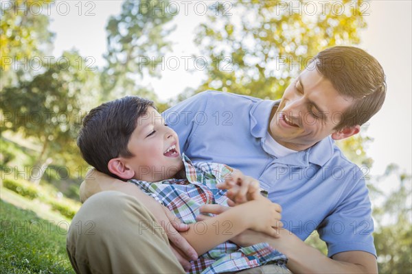 Loving young father tickling son in the park