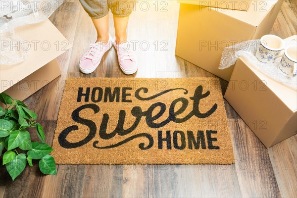 Woman in pink shoes and sweats standing near home sweet home welcome mat