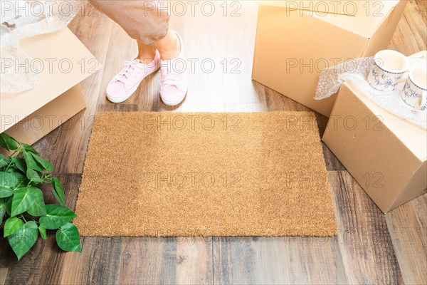 Woman in pink shoes and sweats standing near home sweet home welcome mat