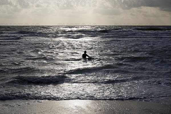 Surf rider goes with her surfboard into the North Sea