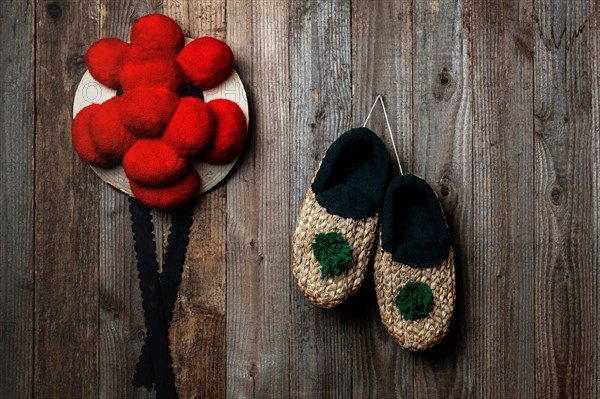 Original Black Forest Bollen hat with straw shoes in front of rustic wooden wall