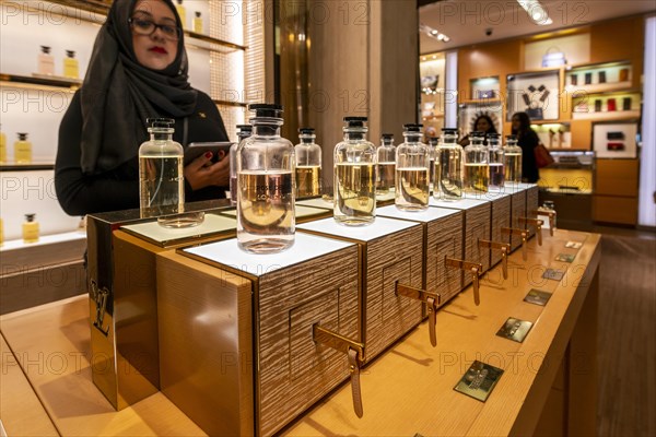 Woman with headscarf looking into lined up perfume bottles