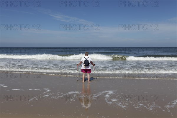 Lone beach walker looking out to sea