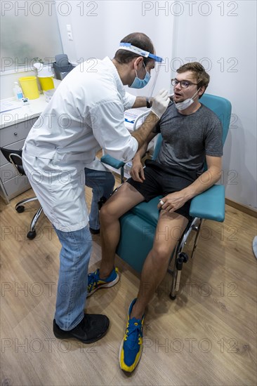 Doctor in protective clothing does an antigen test on a young man