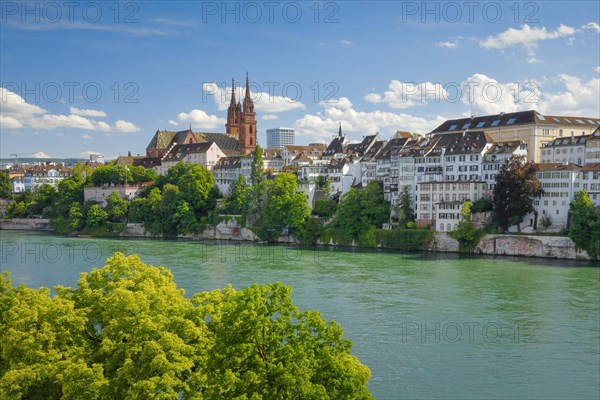 View of the Basel Cathedral in the middle of the old town of Basel with the turquoise Rhine River in the foreground