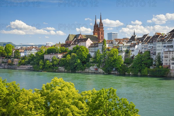 View of the Basel Cathedral in the middle of the old town of Basel with the turquoise Rhine River in the foreground