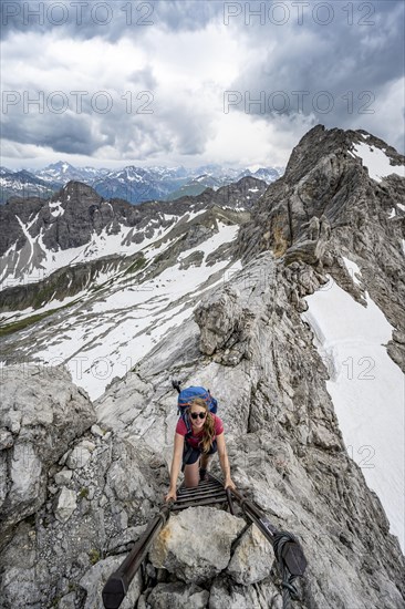 Hiker climbing metal ladder on rock