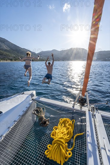 Young woman and young man jumping into the water