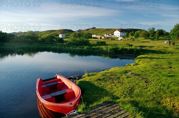 Small red boat on the shore of a lake