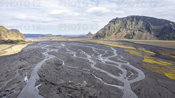 River with fanned out branches through black lava sand