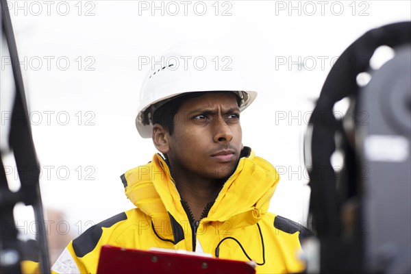 Young technician with helmet and yellow protective jacket working outside
